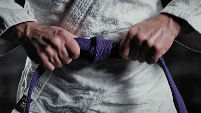 Martial Artist Tying Purple Belt Around Waist.