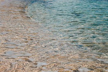Clear shallow water gently lapping on pebbled beach