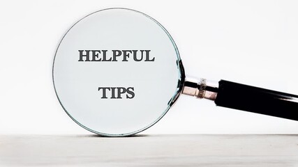 A magnifying glass gradually brings HELPFUL TIPS into focus. The simple message is showcased against a clean, white background in a well-lit studio environment