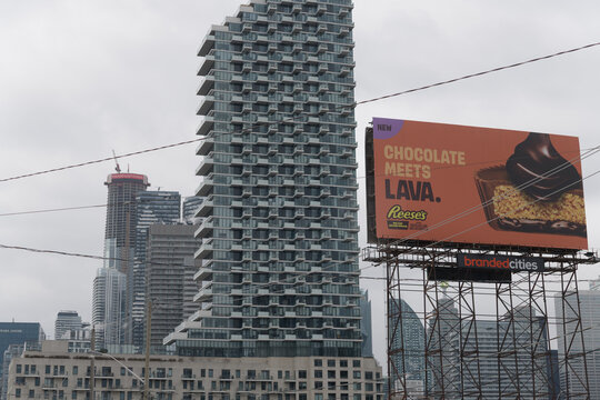 east elevation of Monde Condominiums (located at 12 Bonnycastle St, viewed from Queens Quay E) and an oversized roadside billboard (Reece's chocolates), Toronto