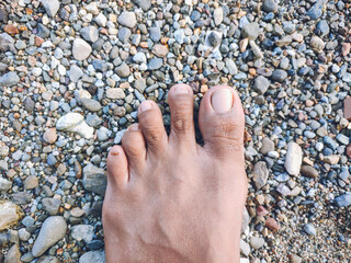 A close-up shot of a bare foot resting on a bed of pebbles, capturing a sense of natural simplicity and grounding