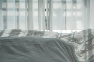 Closeup of beautiful white shiny crumpled  fabric sheets on the bed