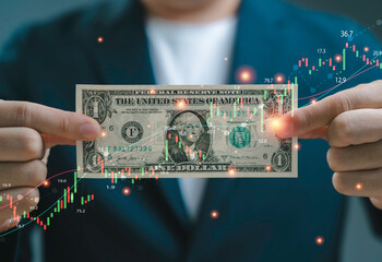 Hands holding US dollar banknote with digital trading charts and financial data overlay...