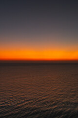 Minimalist ocean sunset with a smooth orange and blue sky gradient above calm sea water, creating a peaceful abstract seascape ideal for background, meditation, nature, and atmospheric design concepts