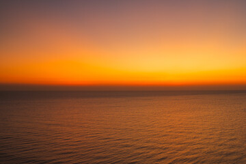 Minimalist ocean sunset with a smooth orange and blue sky gradient above calm sea water, creating a peaceful abstract seascape ideal for background, meditation, nature, and atmospheric design concepts