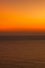 Minimalist ocean sunset with a smooth orange and blue sky gradient above calm sea water, creating a peaceful abstract seascape ideal for background, meditation, nature, and atmospheric design concepts