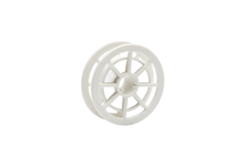 Isolated shot of a white plastic wheel shape with detailed spoke design on flat surface