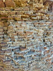 Ancient weathered red brick wall with crumbling mortar texture, showcasing historic architecture and aged masonry detail.