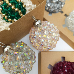 Collection of elegant handmade Christmas balls made of crystal  beads of different colors. Festive holiday decorations displayed in gift boxes . Luxury winter decor concept