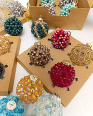 Collection of elegant handmade Christmas balls made of crystal  beads of different colors. Festive holiday decorations displayed in gift boxes . Luxury winter decor concept
