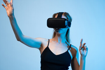 Female user experiencing virtual reality with headset and hand gestures, futuristic immersive technology and digital interaction concept