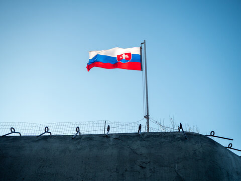 Slovak national flag flying above a historic concrete military bunker in Petržalka, Bratislava, Slovakia, part of preserved prewar and Cold War fortifications.