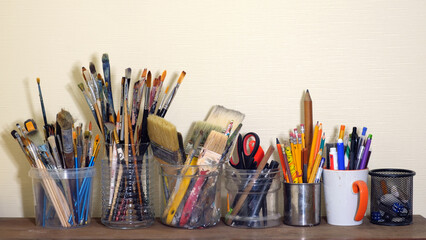 Collection of various art supplies, predominantly paintbrushes and drawing tools, stored in different containers