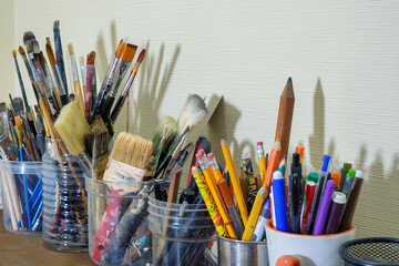 Collection of various art supplies, predominantly paintbrushes and drawing tools, stored in different containers