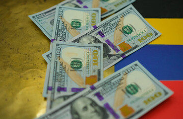 United States dollars on the national colors of the Venezuelan flag background. Grunge gold and black colors, as oil black gold. Shallow depth of field.