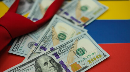 United States dollars and a red necktie on the national colors of the Venezuelan flag background. Shallow depth of field.
