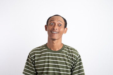 Portrait of overjoyed young bearded dark skinned guy looking at camera with wide eyes opened and holding hand on his belly while laughing happily, isolated over white background