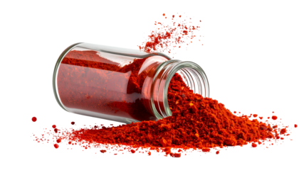 Overturned glass spice jar spilling vibrant red powder onto a surface, against black