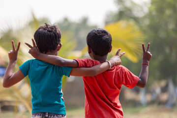 Two small boys are hugging together, with gestures of victory.
