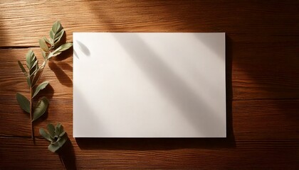 White card on wooden table with leaves and sunlight shadows.