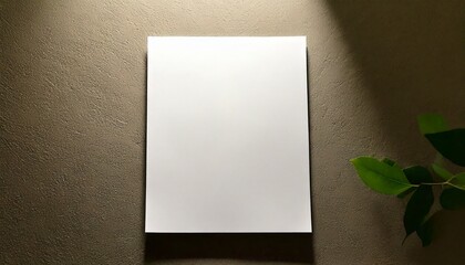 Blank white card on a dark surface with green leaves.
