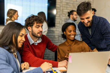 Four business professionals looking at tablet with colleagues in background
