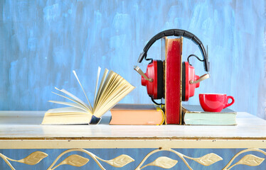audiobooks concept with  stack of books, vintage headphone, a cup of coffee and an open book, free copy space