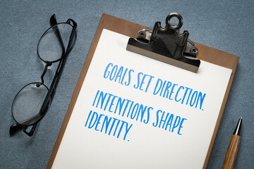 Goals set direction. Intentions shape identity. Goal setting concept on a clipboard.