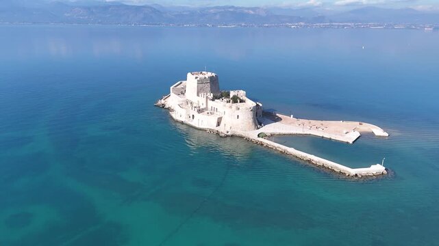 Aerial orbit shot circling Bourtzi water castle in Nafplio harbor, Greece