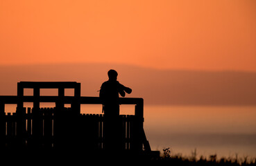Silhouette of photographer capturing sunset on a viewing deck