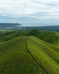 Obraz premium drone shot of green hill and blue sky