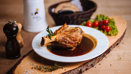 Braised meat shank in rich gravy served on white plate