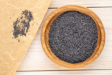 Dry poppy seeds with kitchen utensils on a wooden table, close-up, top view.