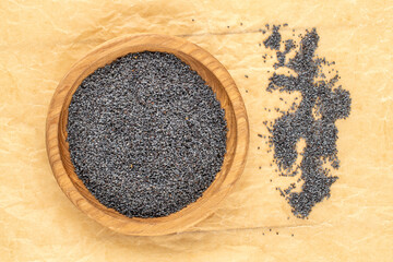 Dry poppy seeds with kitchen utensils on kraft paper, close-up, top view.