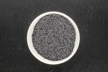 Dry poppy with kitchen utensils on slate stone, macro, top view.