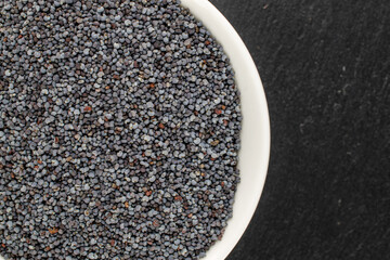 Dry poppy with kitchen utensils on slate stone, macro, top view.