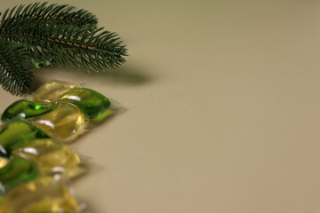 Colorful detergent pods arranged on a plain surface with a green pine branch nearby