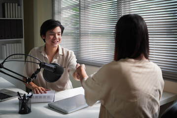 Two people connect as host and guest during a podcast session, sharing a welcoming moment in a recording space