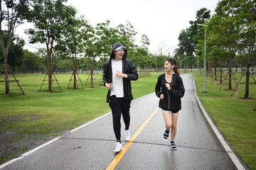 Two friends jog along a park path after rain, enjoying exercise, fresh air, and conversation despite the wet weather