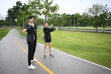 Two friends stretch on a wet park path after rain, warming up together and enjoying fresh air and light exercise