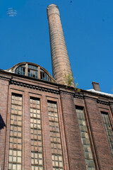 Tall industrial chimney and factory facade