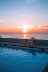 Serene sunset over oceanfront pool view.
