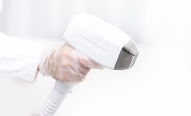 Laser hair removal equipment in use by gloved hand, studio white light