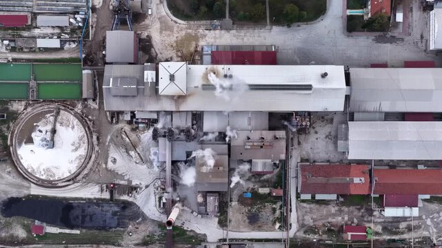 Aerial view of the sugar factory; smoke rising from the chimneys and the production process of the industrial facility. Detailed aerial shot showing the modern industrial infrastructure and smoke comi