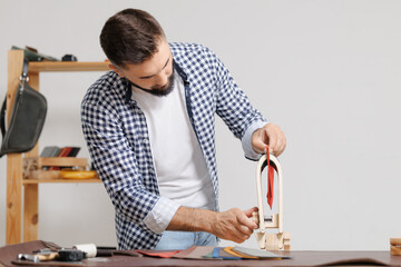 Artisan cobbler use needle for working with leather textile for shoe at his workshop.
