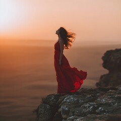 Elegant Woman in Red Dress Overlooking the Landscape from a Cliff at Dawn