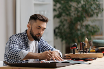 Obraz premium Male tailor working with leather materials in workshop, hand made craft diy product