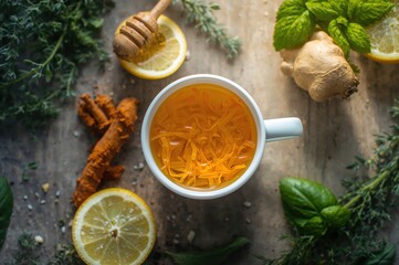 Steaming ginger lemon tea with turmeric honey and fresh herbs overhead