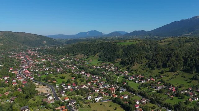 Sweeping Aerial Panorama of Moieciu de Jos Village and Winding Rucar-Bran Pass Road under Bucegi Mountains in Transylvania