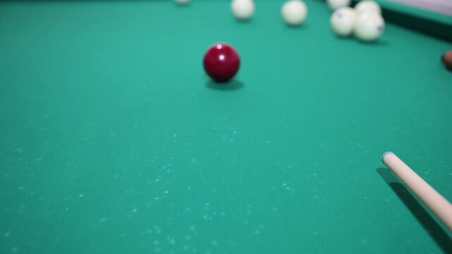 Hitting the ball with a cue and hitting the hole on the green background of the billiard table